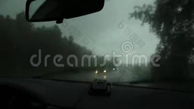 在恶劣的雨天驾驶，在汽车行驶过程中通过挡风玻璃观看乡村道路。 窗外的雨滴